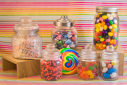 Still life of a variety of candy jars filled with colorful confections.