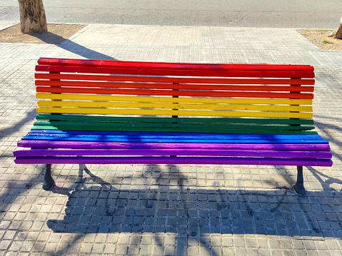 Wooden bench painted in rainbow colors at a harbor, port