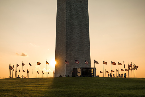 horizontal shot of washington memorial with the flags in blue sky and at sunset
