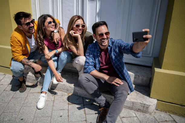 istock Cheerful friends sit on the steps and take selfies 1410905332