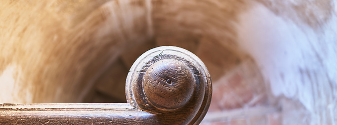 detail of a top view of a stone spiral staircase with a wooden handrail