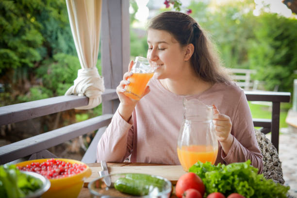 istock woman making fresh vegetable salad and drinking fresh orange juice 1410908523