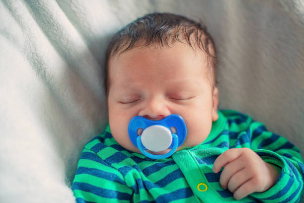 istock sleeping newborn baby with a pacifier in his mouth close-up 1410909307