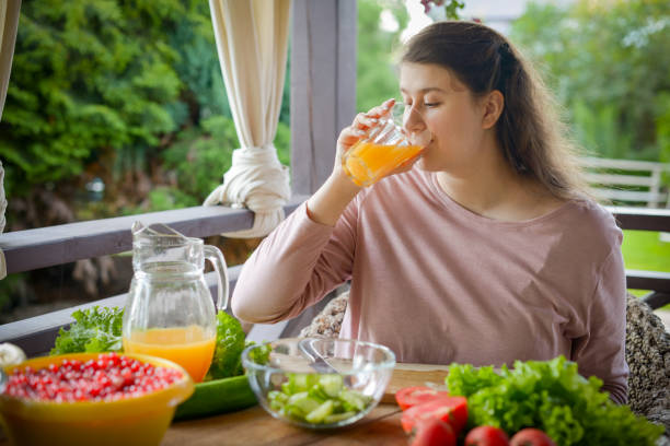 istock woman making fresh vegetable salad and drinking fresh orange juice 1410909329