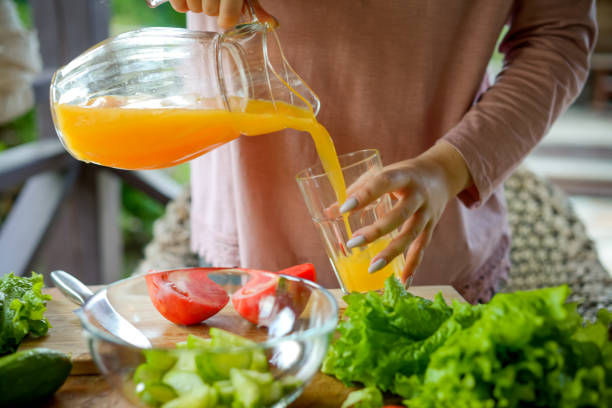 istock woman making fresh vegetable salad and drinking fresh orange juice 1410910034