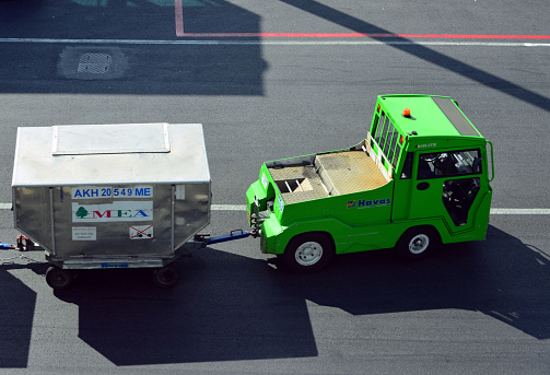Istanbul, Turkey: tractor with Unit Load Device (ULD) loaded over a cargo dolly. ULD is a standardized container for storing aircraft baggage or cargo. MEA / Middle East Airlines Air Liban cargo and Havas tractor.