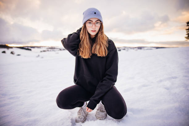 adolescente donna inginocchiata nel paesaggio invernale della foresta nera ritratto di persone reali - brown hair caucasian clothing color image foto e immagini stock