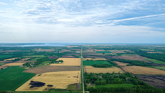 A rural summertime view of wisconsin with farmland and fields. A lake far in the distance.