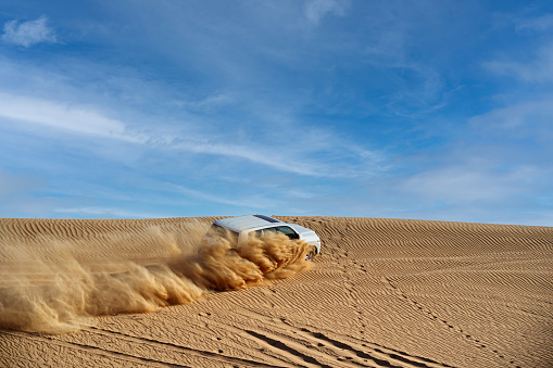 Drifting off road car 4x4 in desert. Freeze motion of exploding sand powder into the air. Action and leasure activity.