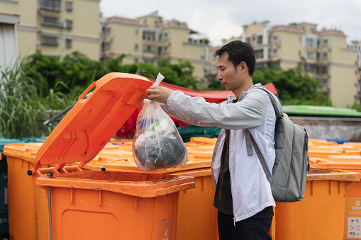 Asian man throwing rubbish into trash can