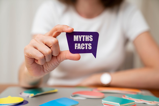 Woman wearing white t-shirt holding paper card bubble. Myths and Facts message on speech bubble.