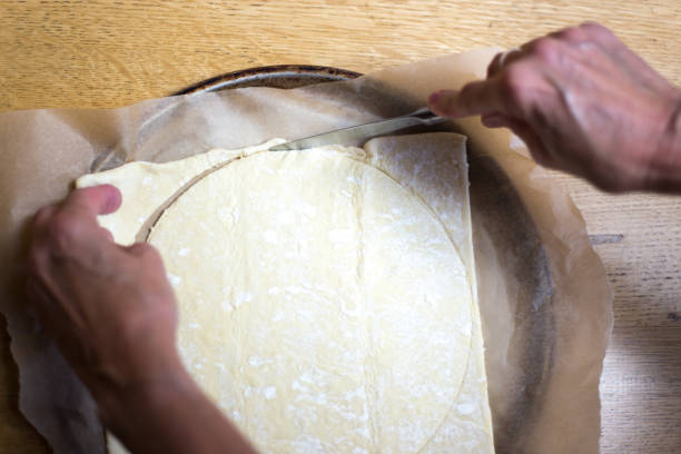 istock Hands Cutting Pastry Dough Round for Tart 1410932926