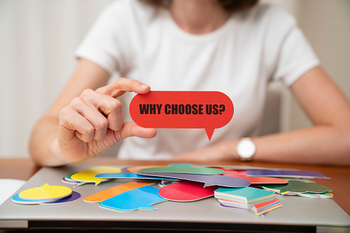 Woman wearing white t-shirt holding paper card bubble. Why choose us message on speech bubble.