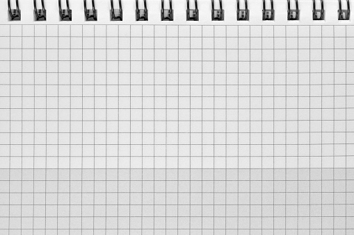Checked spiral notebook grey white background pattern, horizontal chequered squared open notepad copy space, stapled blank empty blocknote, reminder concept metaphor, large detailed macro closeup