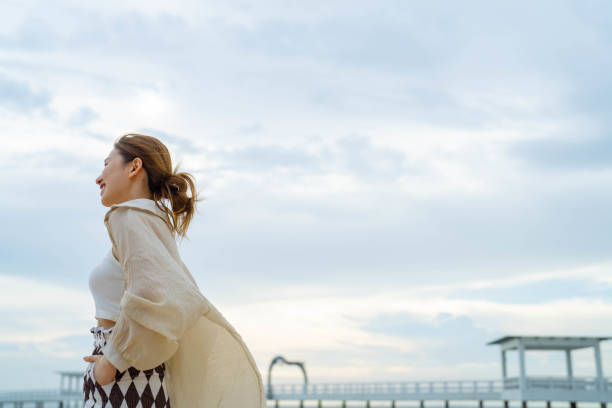 Girl in dress on the pier at lifebuoy looking at the sea