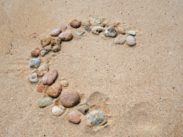 istock Set of colorful pebbles forming a shape on beach sand background 1410953973