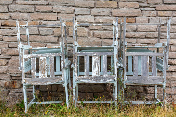 istock Old leftover garden chairs stacked by a wall 1410955098
