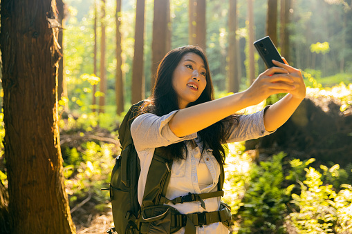 Young woman taking a selfie with mobile phine hiking in a forest