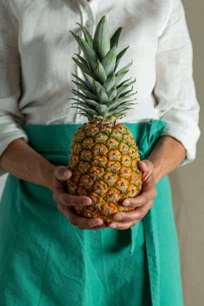 istock Woman holding pineapple with plain background - stock photo 1410956241