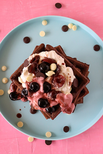 Delicious homemade oatmeal waffle with creamy natural yogurt, honey, banana and chopped chocolate on a white background.