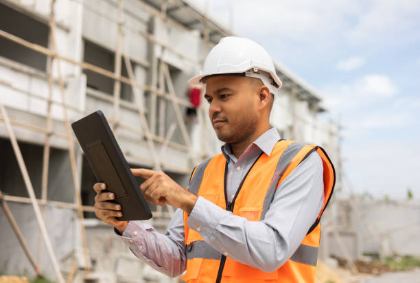 istock Confident asian engineer man Using tablet for checking and maintenance to inspection at modern home building construction. Architect working with white safety helmet in construction site 1410957505