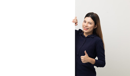 Portrait of Young beautiful mixed race woman standing and smiling on isolated white background with big mockup billboard for advertising text.