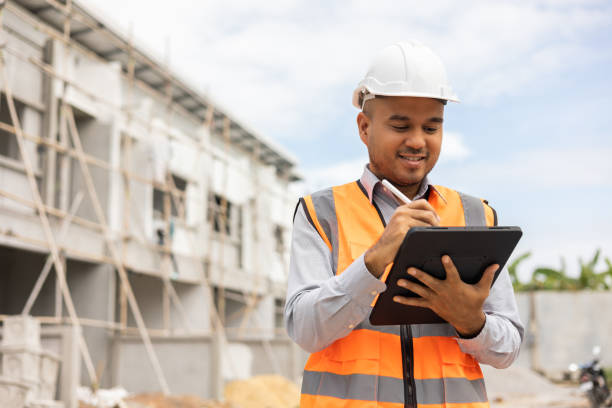 istock Confident asian engineer man Using tablet for checking and maintenance to inspection at modern home building construction. Architect working with white safety helmet in construction site 1410957635