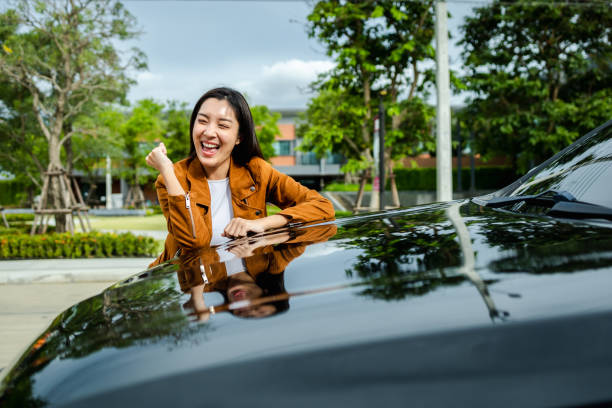 junge schöne asiatische frau, die das neue auto bekommt. sie umarmte ihr auto und war sehr glücklich. auto-konzept kaufen oder mieten. - driving new car driver stock-fotos und bilder