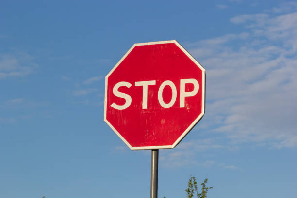 istock Red Stop Sign with Blue Sky and Clouds Background 1410958558