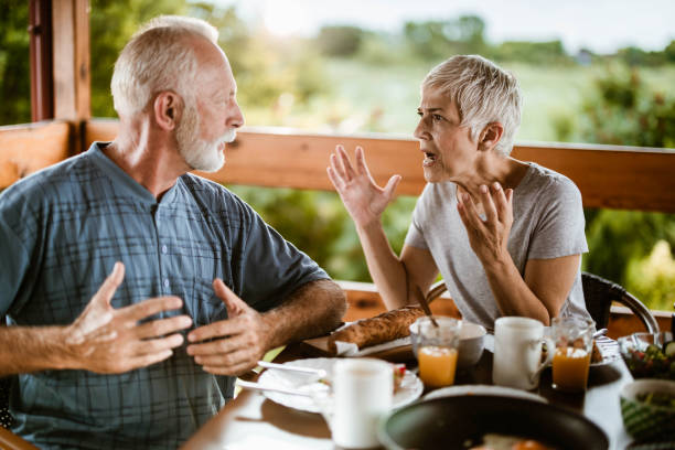 Angry mature couple arguing during breakfast on a terrace.