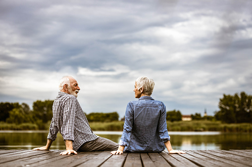 Happy mature couple communicating on a pier at lake. Copy space.
