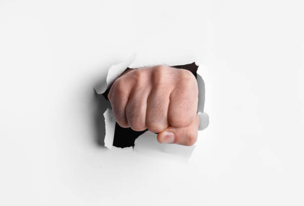 istock Man breaking through white paper with fist, closeup 1410959835