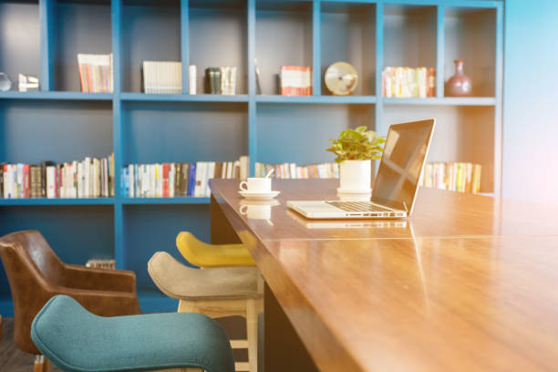 istock Shared large desk and bookshelf with laptop and coffee 1410961313
