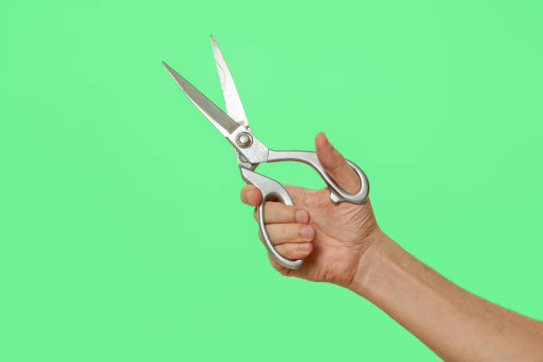 istock Scissors in hand isolated on green screen background 1410963393