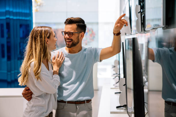 istock Happy people in consumer electronics retail store looking at new digital device 1410965546