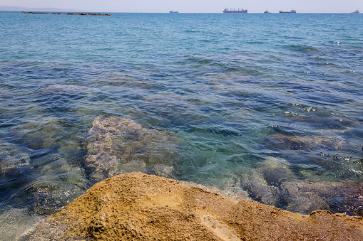 Aquamarine sea water with rocks underwater and ships on the horizon