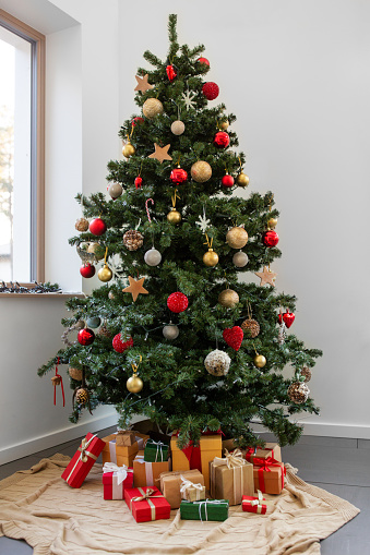 Festive Christmas and New Year celebration ornament concept: Close-up on beautiful xmas tree decoration lights, glass ball and toys hanging on artificial pine branches. Decorative holiday background, copy space.