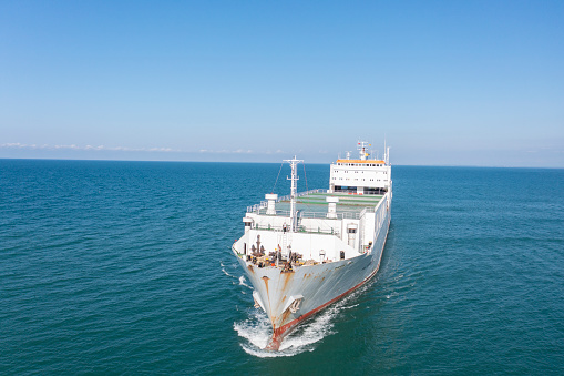 Aerial view of a heavy loaded cargo vessel traveling over calm, blue sea.