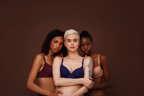 три женщины разного цвета кожи стоят вместе. группа молодых самок в нижнем белье на фоне. - st petersburg стоковые фото и изображения