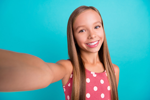 Photo of sweet shiny little lady dressed dotted sarafan recording self video smiling isolated teal color background.