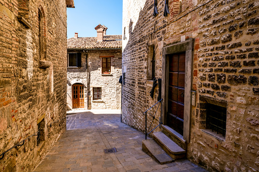 A suggestive and beautiful stone alley in the historic heart of Gubbio, a medieval town in Umbria, central Italy. Gubbio, an ancient city built on the communication routes between the Tyrrhenian coast and the Adriatic coast of Italy, an ally of ancient Rome, is famous throughout the world for its artistic and medieval treasures, but also for the life of St. Francis of Assisi and the miracle of the encounter with the wolf. The Umbria region, considered the green lung of Italy for its wooded mountains, is characterized by a perfect integration between nature and the presence of man, in a context of environmental sustainability and healthy life. In addition to its immense artistic and historical heritage, Umbria is famous for its food and wine production and for the quality of the olive oil produced in these lands. Wide angle image in high definition format.