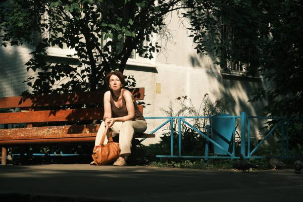 A senior Japanese woman sitting alone on a park bench and looking at the scenery