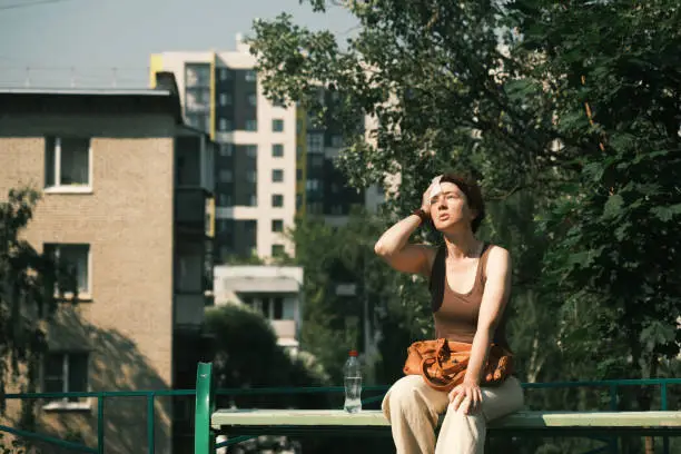 Mature woman is feeling bad during the heat wave in city