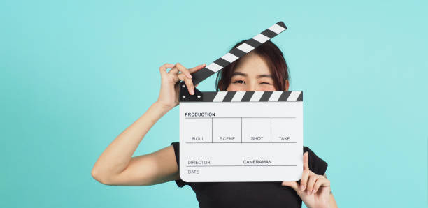 istock Asian Woman holding white clapperboard on mint or Tiffany Blue  background. 1410976697
