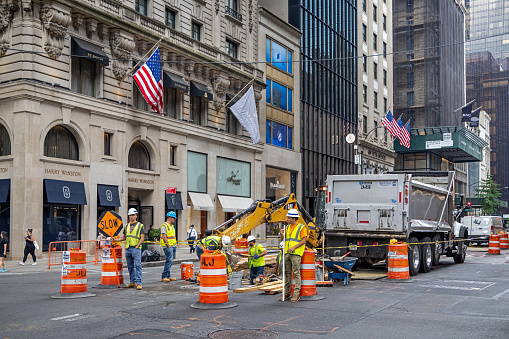 Construction workers in safety helmets and west digging up the asphalt 5th Avenue close to 55th Street in central Manhattan