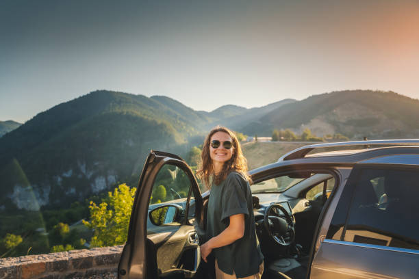 山の中を車で旅する若い美しい女性、夏休み、冒険 - car mount ストックフォトと画像