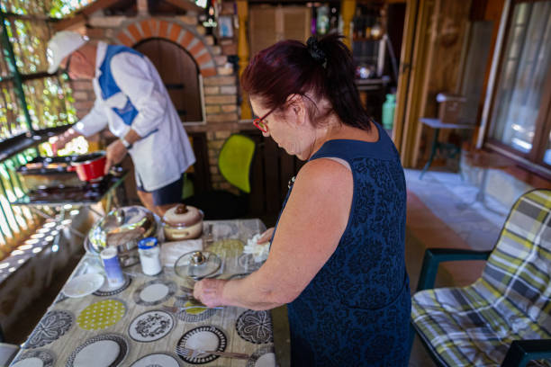 donna anziana che assiste il marito in cucina - looking at camera full length outdoors image technique foto e immagini stock