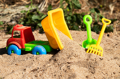 Colorful children's beach toys on sand background