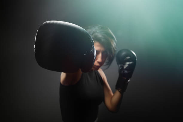 Fit and muscular female fighter ready to fight. Showing her fists in a defensive boxing pose Fit and muscular female fighter ready to fight. Showing her fists in a defensive boxing pose boxercise stock pictures, royalty-free photos & images