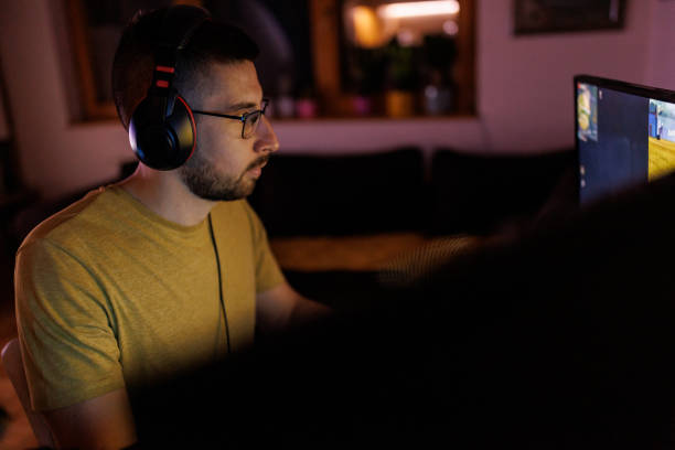 istock Young man livestreaming while playing multiplayer online game in the evening at home 1410982479